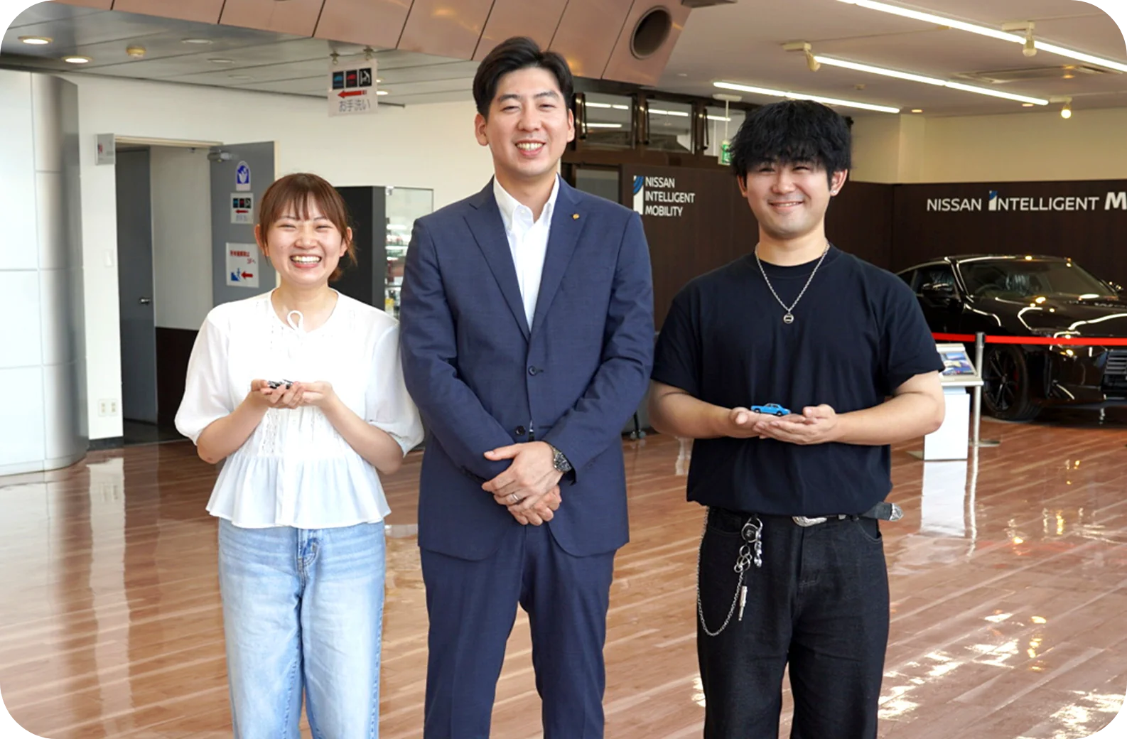 ショールームに並ぶ社長と学生2人